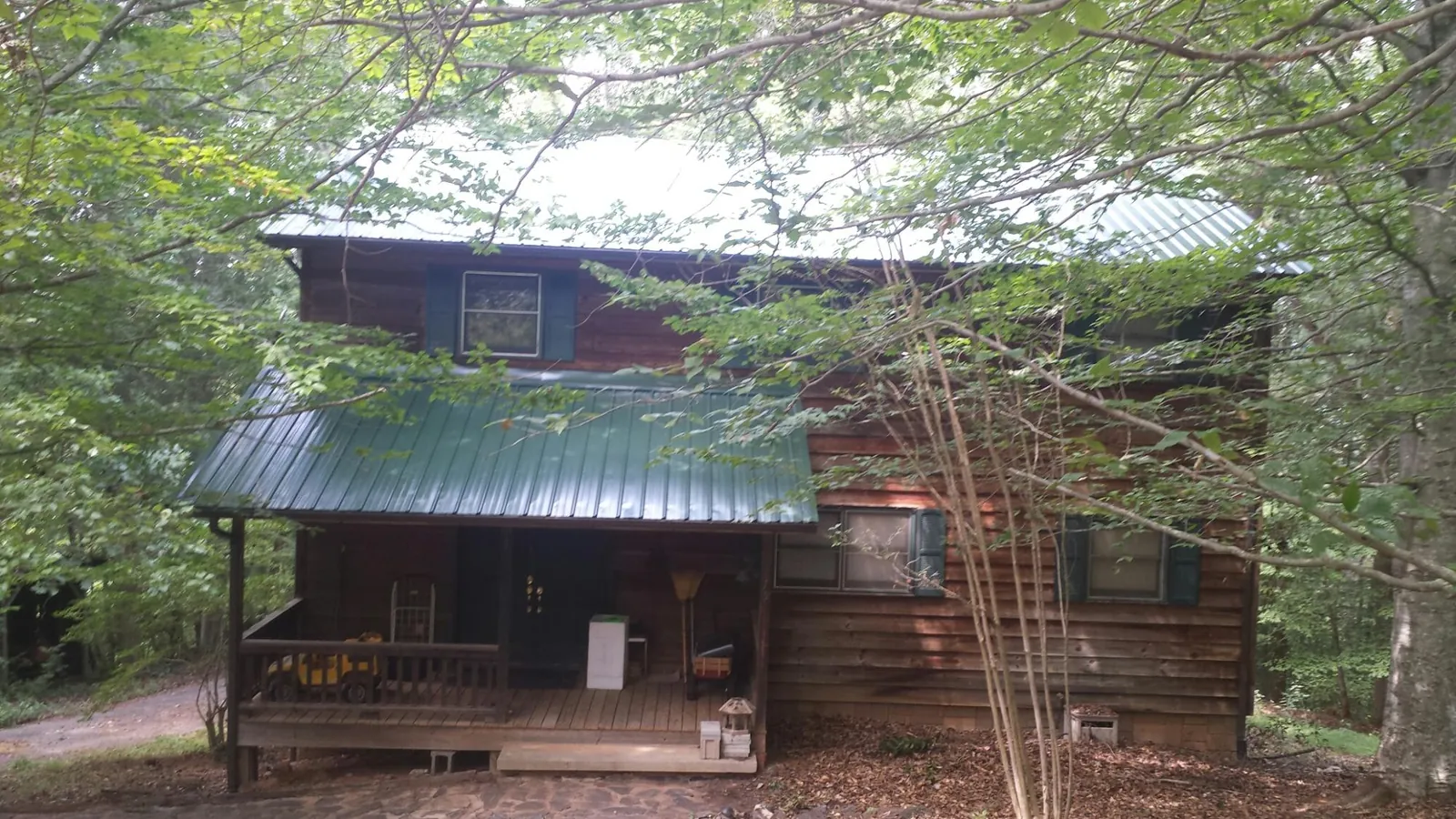 Green metal roof and covered porch on a log cabin in Young America