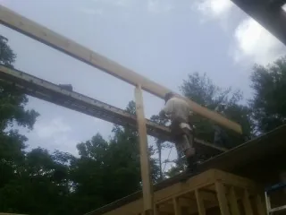 Carpenter setting a ridge beam over a new addition frame — Ice Dam Removal by Roofing Brothers in Young America