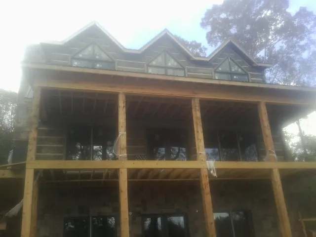 Dormers and porch framing on a large log home under construction — Roof Coating work by our crew in Young America