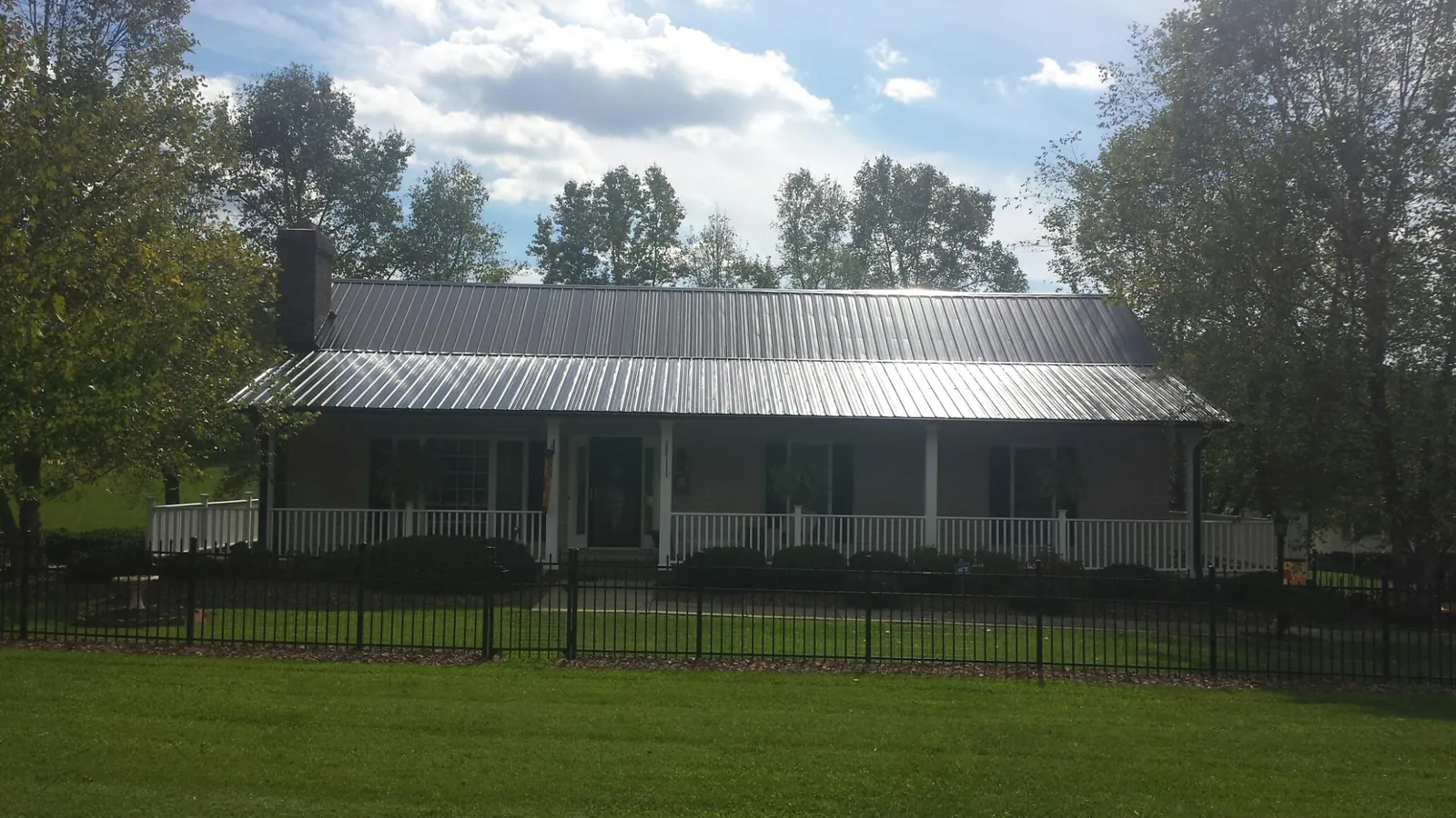 Gray metal roof on a brick ranch with a full width front porch — Gutter Guard Installation work by our crew in Young America