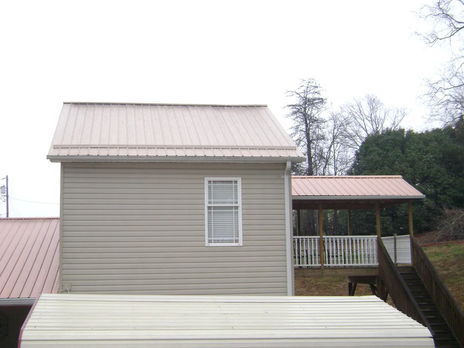 Tan metal roofs on a two story addition and attached porch, from a Roof Replacement job in Young America