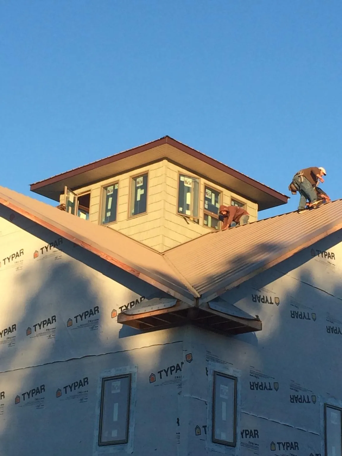 Roofers working around a rooftop cupola on a new metal roof at sunset — Roof Waterproofing in Young America by Roofing Brothers